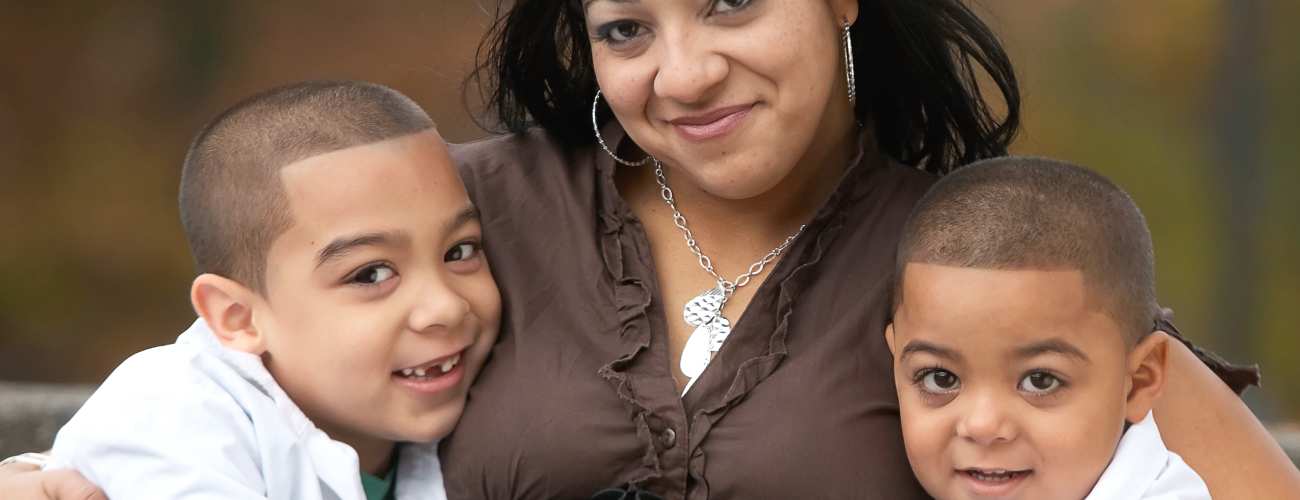 Hispanic foster mom with arms around two young foster boys