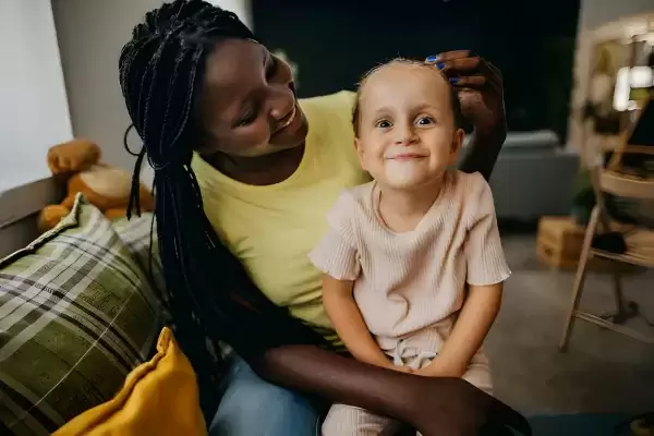 African American foster Mother with a foster child on her lap smiling 