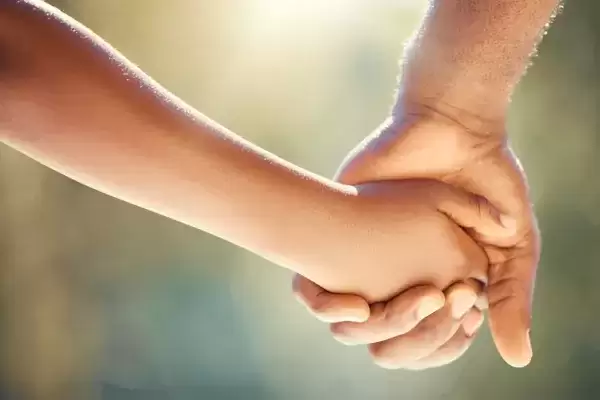 Close up foster father and child holding hands while outside