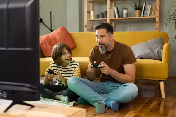 Foster Father and son playing video games in livingroom 