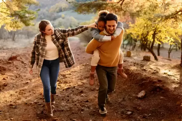 Foster family with small foster child hiking outdoors in autumn nature