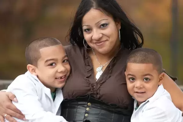 Hispanic foster mom with arms around two young foster boys