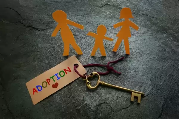 keys on a table with a paper cut out family around the keys that have a label of adoption on it