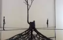 A metal tree with two type ropes with two metal figures standing on rope