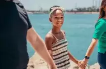 Africian American foster child holding hands with two foster parents