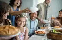 Foster daughter sitting at dinner table surrounded by loving foster family