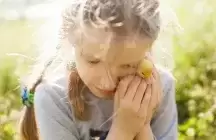A young foster child hugging a baby chick to her face