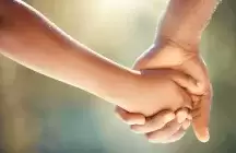 Close up foster father and child holding hands while outside