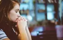 Young lady praying in church for guidance about becoming a foster parent