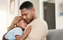 Foster dad hugging foster son sitting on a chair 