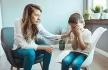 A mum of a foster child sitting on a chair next to child