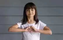 Foster child with a heart on her chest made from her hands