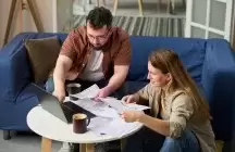 Foster parents siting at a small table doing taxes with laptop