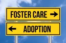 Yellow road sign with foster care and Adoption pointing left and right
