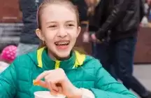 Foster child eating lunch in a green jacket