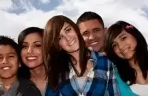five teenagers hugging with a sky background 