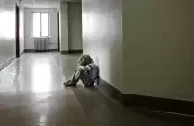 A foster child siting in a dark corridor 
