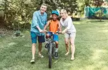 foster parents supporting a child on a bike