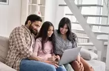Foster family sitting on a couch looking at a computer
