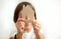 Little girl holding paper house in front of her face