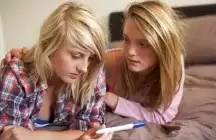 Foster child with friend looking at a pregnancy test looking stressed