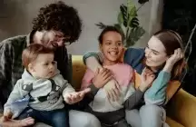 Smiling foster child sitting with foster family on a couch
