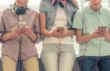 foster teens sitting on sill with phones in their hands 