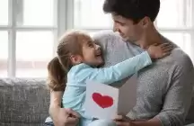 A foster parent receiving a card with a red heart on it from a child