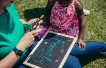 Foster parent and toddler writing family on a chalk board