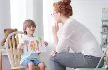 Foster parent looking a Child holding up a drawing 