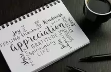 A pad with appreciation words written on it by a cup of coffee on a table