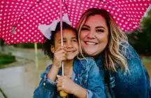Foster child with foster mother holding a pink Poka dot umbrella 