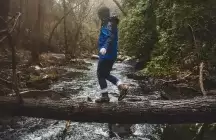 Teenager walking across a log over a river