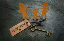 keys on a table with a paper cut out family around the keys that have a label of adoption on it