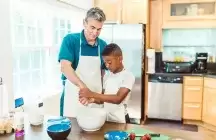 Foster Dad helping a child in the kitchen.